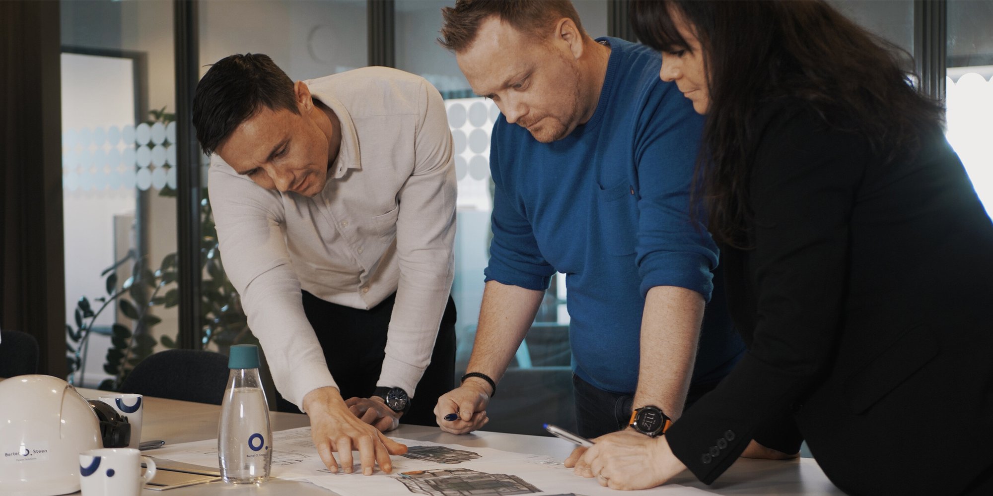 Et team på tre personer samarbeider om dokumenter på kontoret. Et team på tre personer samarbeider om dokumenter på kontoret.