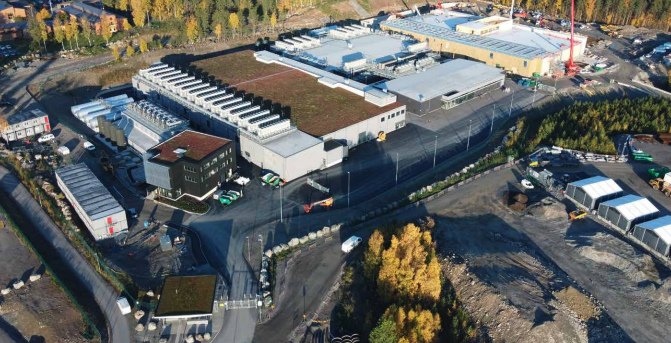 Flyfoto av EcoDataCenters campus med flere bygninger og trær om høsten. Flyfoto av EcoDataCenters campus med flere bygninger og trær om høsten.